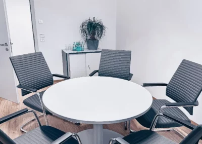 Ein Konferenzraum mit einem runden Tisch und Stühlen.
